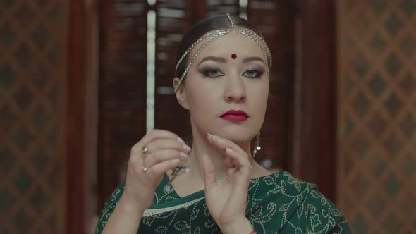 Portrait of Stylish Indian Woman Putting Earrings alt