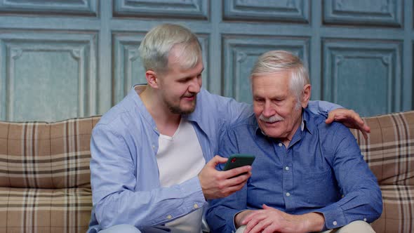 Happy Family Senior Father and Son Watching on Mobile Phone to Internet Online with Fun Together alt