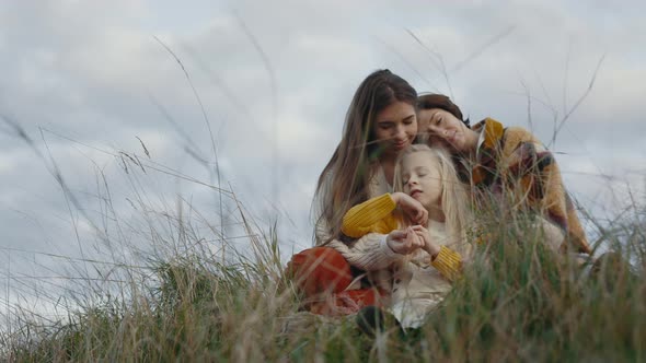 Happy Couple of Lesbians Sitting in Embrace with Daughter alt