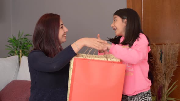 Little girl giving a gift to her mother. alt