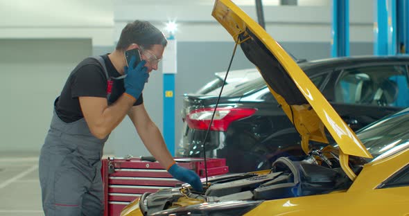 Mechanic Calls Customers for Communication, in the Car Service Center. Concept Repair of Machines