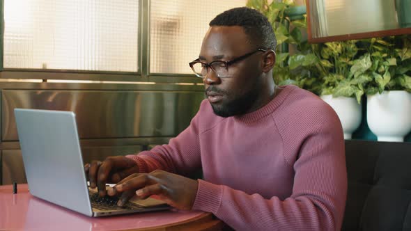 Afro-American Man Typing on Laptop in Cafe alt