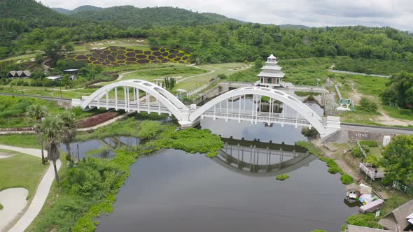 Aerial top view of Tha Chomphu White Bridge, Lamphun, Thailand with lake or river alt