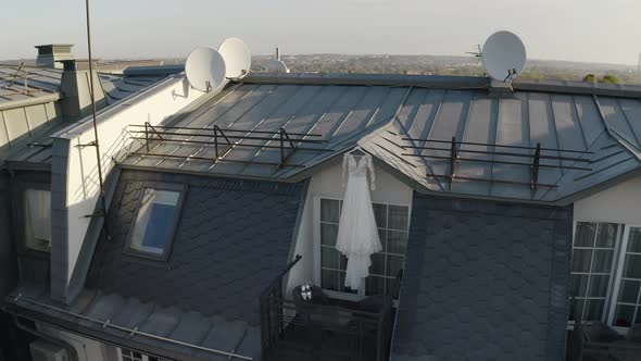 Wedding Gown Dress Hanging at Balcony Terrace Doorway Waits for Bride at Sunny Morning Aerial View alt