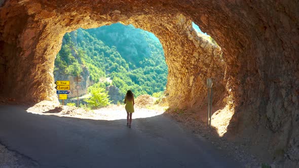 A Girl in a Yellow Dress Walks Through a Rocky Tunnel in a Mountain in Montenegro alt