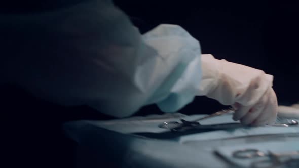 Assistant Handing Surgery Tools to Practitioner Dark Operating Theater Closeup alt