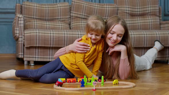 Mother Playing with Child Kid Daughter Riding Toy Train on Wooden Railroad Blocks Board Game at Home alt