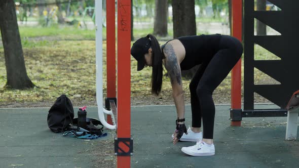 Athletic Woman Warming Up Before Training on the Playground in the Park alt