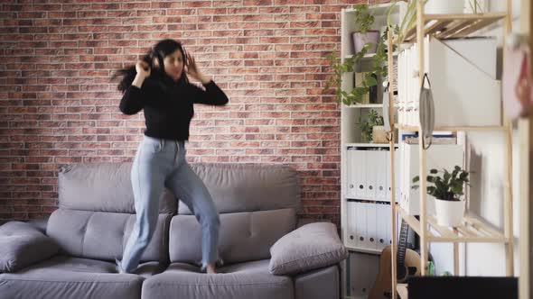 woman dancing on a couch in her house alt