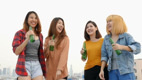 Group of Asian young women dancing and clinking bottles of beer party on the rooftop.