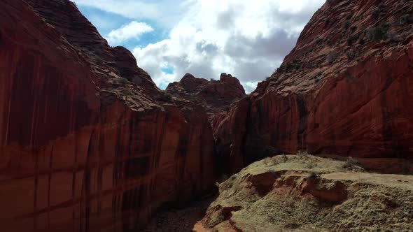 Drone flying low inside a red rock slot canyon. Drone slowly going up to capture the red isolated la alt