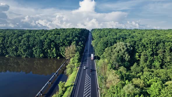 Car Driving Down an Asphalt Road Crossing the Vast Forest alt