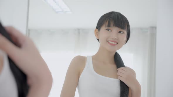 Beautiful face of young asian woman with happy smiling and touch cheek looking mirror. alt