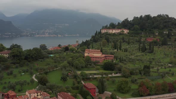 Aerial over green mountain near the city of Bellagio, Italy and revealing a vast and stunning lake alt