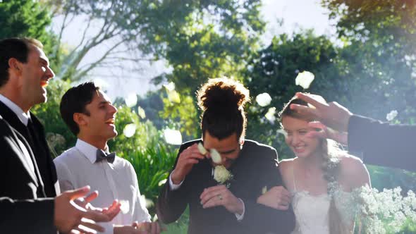 Bride and groom walking down while guests toss petals alt