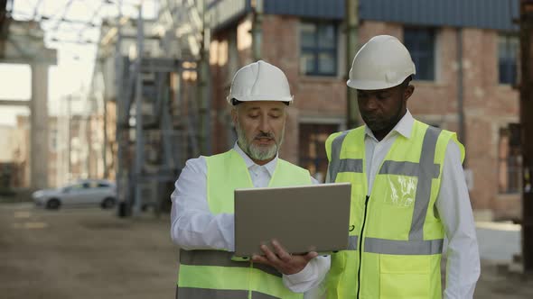 Architect with Laptop Explaining Ideas to Worker Outside alt