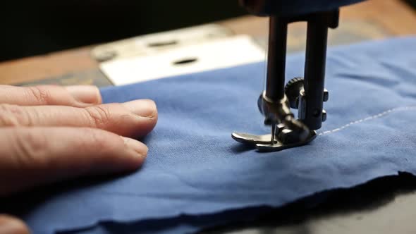 Seamstress Sewing On A Blue Fabric Close
