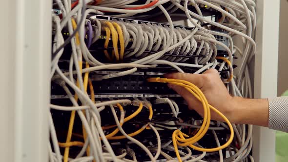 Male IT Technician Working On  Switch Router Standing Open Server Rack Cabinet in Big Data Center. alt