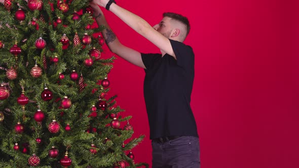 Young Gay Couple Hanging Decorations On Christmas Tree Together