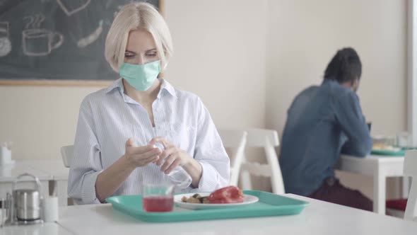 Beautiful Caucasian Woman Disinfecting Hands with Sanitizer on Meal in Lunchroom Drinking Juice alt