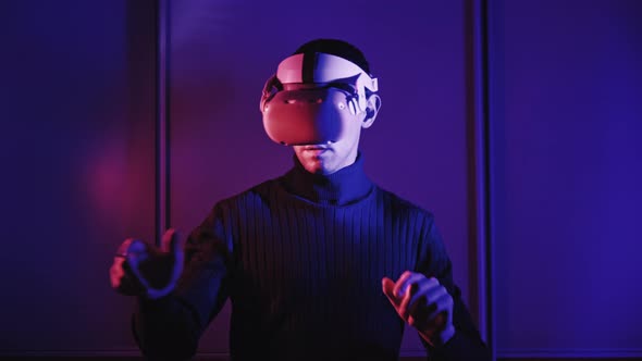 Young Man in a VR Helmet Interacts with Virtual Reality and 360 Media Content alt