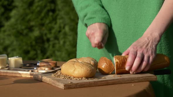 Female in green sweater cut bread for snacks for outdoor party
