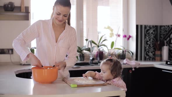 Mother Cooking Together with Little Daughter at Kitchen