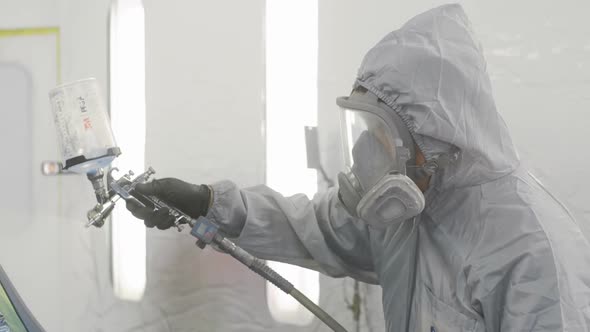 Auto painter painting top of car in paint chamber alt