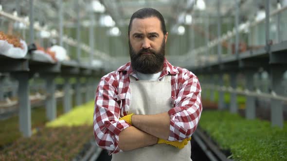 Serious Farmer Staring at Camera in Greenhouse Concerned About Business Problems