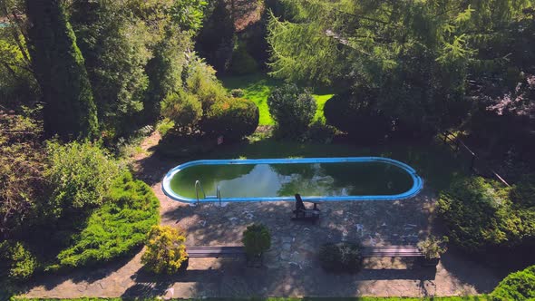 Old Abandoned Swimming Pool with Dirty Green Water. Flight Over a Beautiful Green Area with an alt