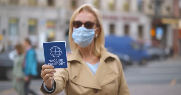 Portrait of Mature Woman in Face Mask Showing at Camera Vaccine Passport alt