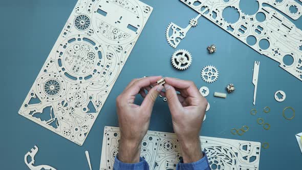 Game concept. Mechanical wooden puzzle toy. Man holding small toy pieces in hands alt