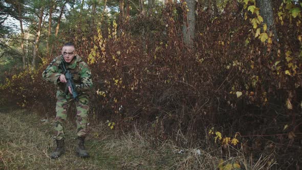 The Hunter Climbs Out of the Bushes and Aims a Gun at an Object in the Forest alt