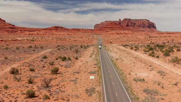 Aerial view of a truck towing a camper on a long two lane highway in Utah alt