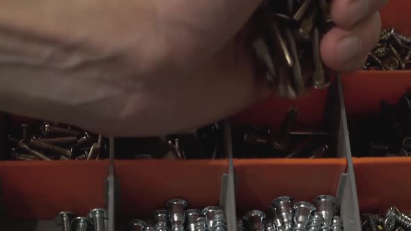Master Who Produces and Installs Furniture Pours Many Bolts Into the Cell in the Suitcase. Close-up alt