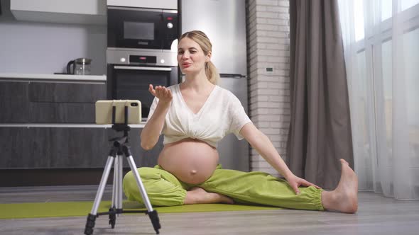 Pregnant Female Blogger Practices Yoga at Home with a Smartphone