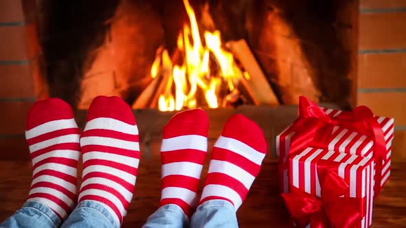 Couple in Christmas Socks Near Fireplace alt