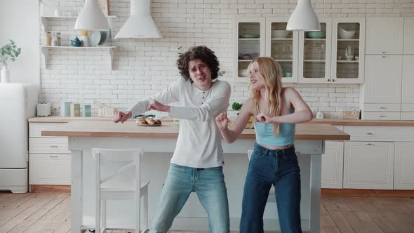 Happy Funky Young Romantic Couple Dancing Jumping in Kitchen alt