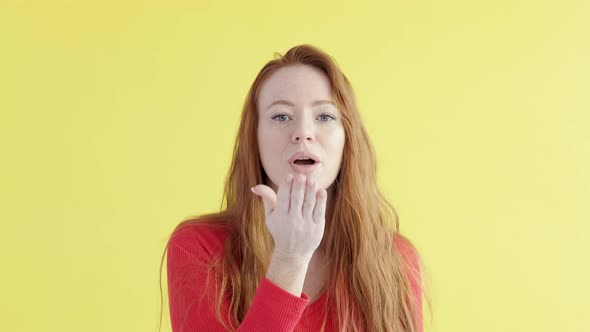 Caucasian cheerful woman with red hair in a good mood blows kiss to camera