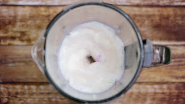Strawberries, Bananas and Milk Are Mixed in a Blender on the Table. View From Above alt