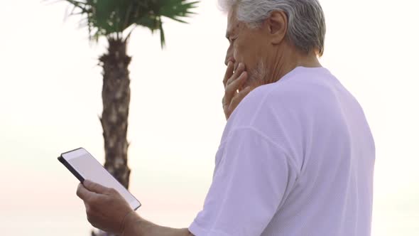 Portrait of Retirement Handsome Senior Man Using Tablet Computer on Seafront alt