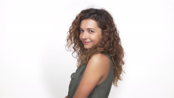 Playful Brunette Lady with Curly Hair Winking at Camera Blinking Her Eye Isolated Over White