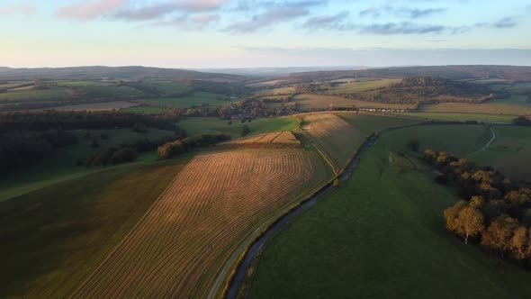 Aerial tilt up shot as the sun sets over the pristine scenery of the South Downs Way, England alt