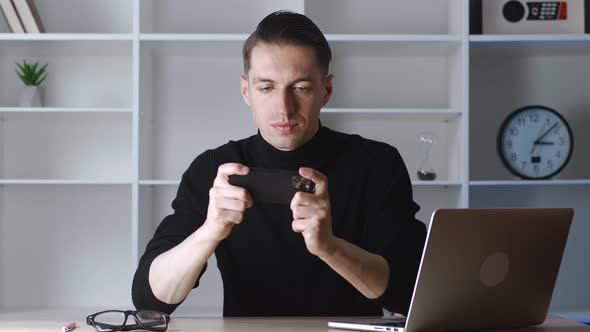 Young Man Playing on His Smartphone Exciting Mobile Application Winning a Racing Game Clenching Fist alt