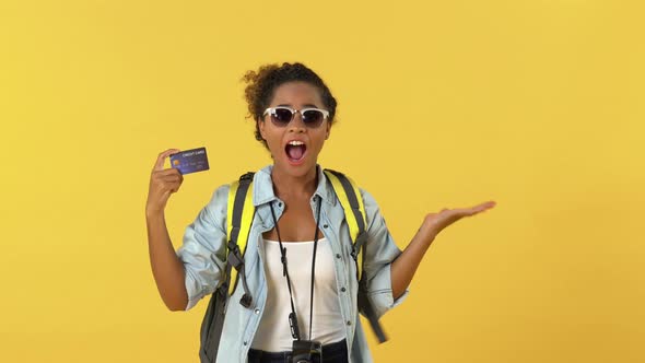 Happy African American woman backpacker holding credit card