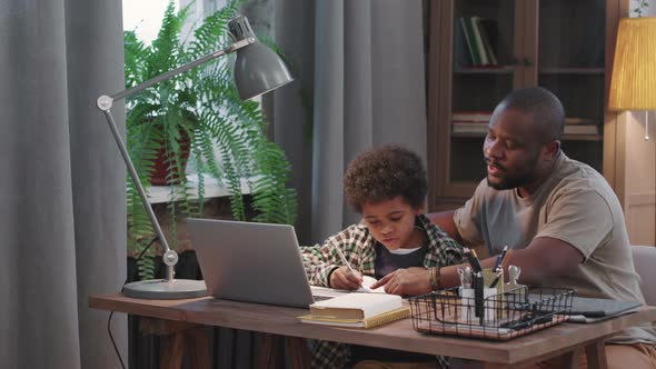Afro-American Man And Little Son Doing Homework Together alt