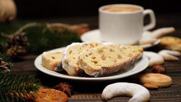 Sliced Traditional Christmas Stollen Cake with Marzipan and New Year Decorations on Wooden alt