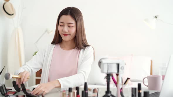 Young beautiful Asian woman professional beauty vlogger doing cosmetic makeup tutorial online