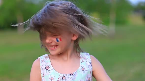 Child Cheerful Girl Happily Shakes Head with Her Cheeks Painted in the Flag of France Her Hair alt