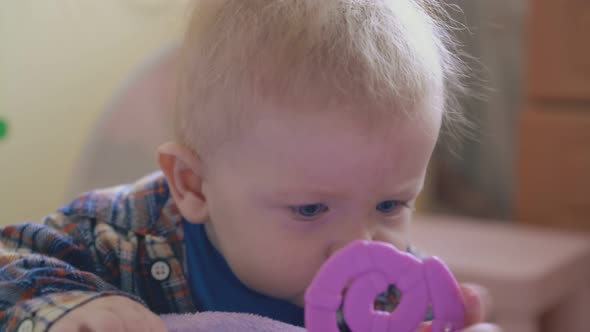 Baby in Warm Shirt Nibbles Teether Climbing on Soft Bed alt